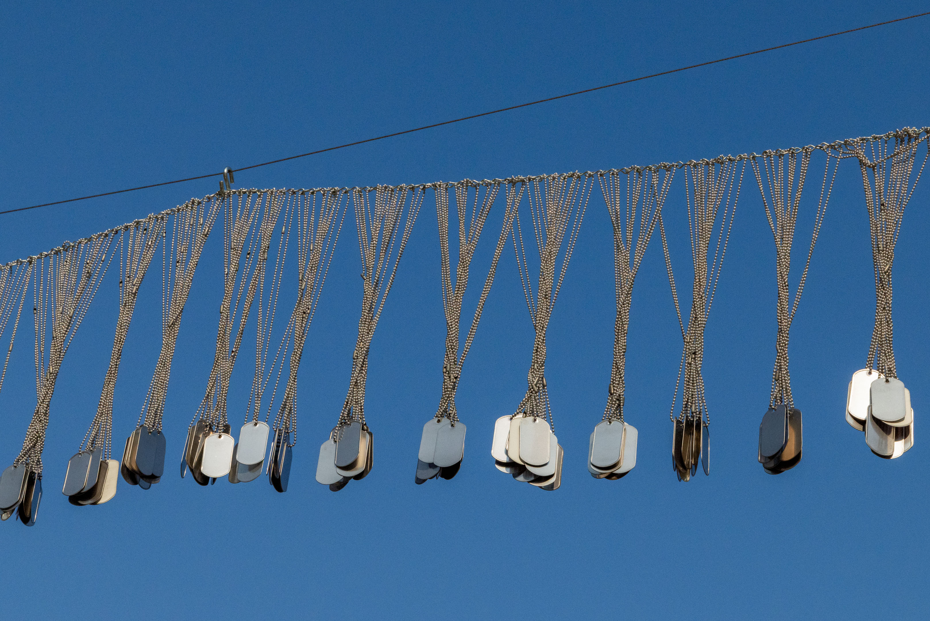 metal name plates hanging on a line with blue sky in the background